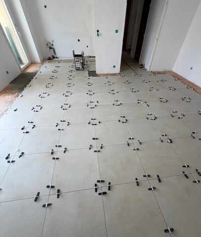 Pose en cours de carrelage grand format avec système de nivellement à croisillons et cales, chantier RJM Rénovation