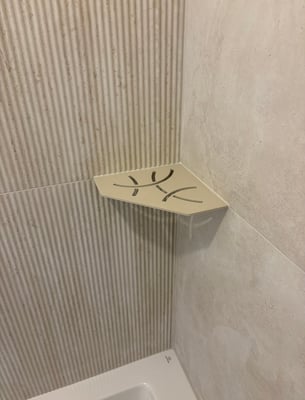 Tablette d'angle intégrée dans une douche carrelée effet travertin par RJM Rénovation