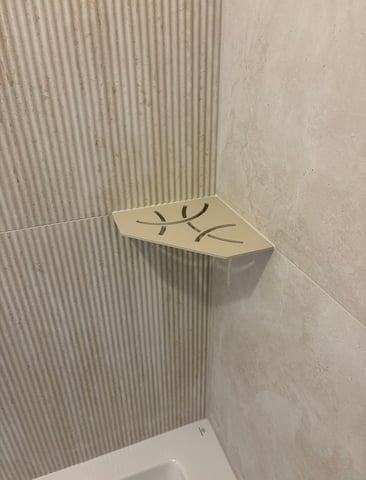 Tablette d'angle en aluminium intégrée dans une douche carrelée effet travertin cannelé par RJM Rénovation
