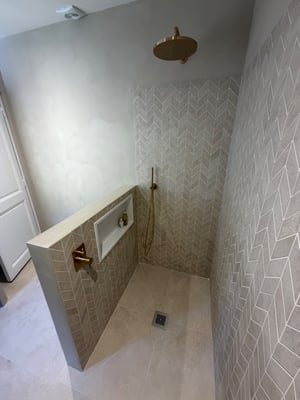 Douche carrelée chevron avec robinetterie dorée, chantier RJM