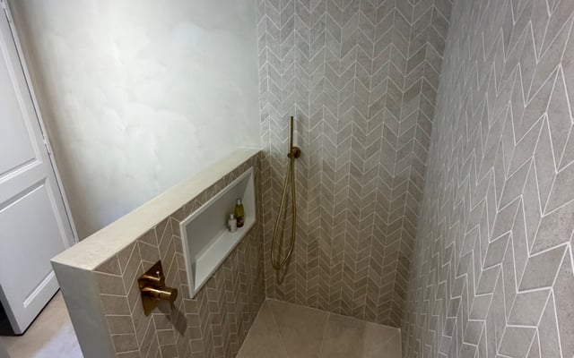 Douche carrelée chevron avec robinetterie dorée, chantier RJM